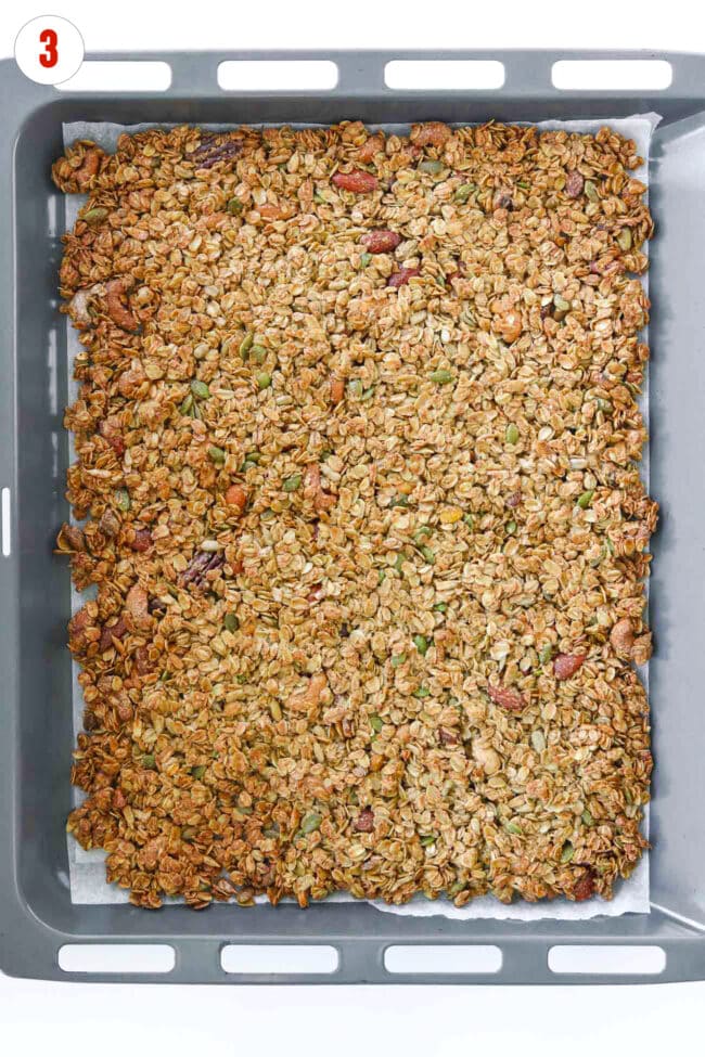 Baked tahini granola on a parchment paper lined rimmed baking tray.