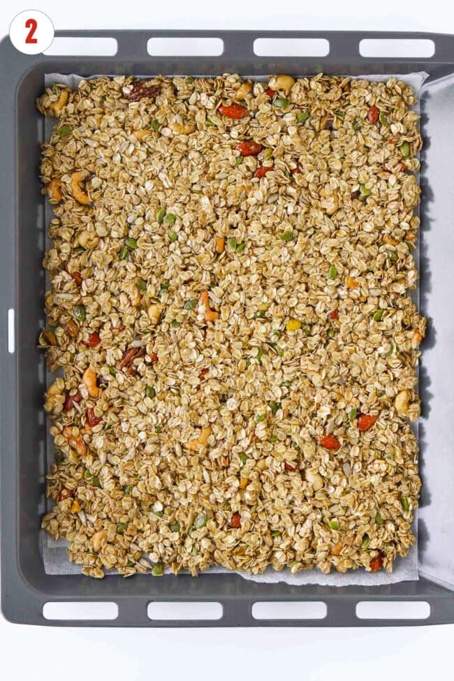 Unbaked maple tahini granola on a parchment paper lined baking tray.