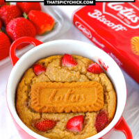 Front view of biscoff baked oats in a ramekin. Text overlay "Biscoff Baked Oats with Strawberries" and "thatspicychick.com".