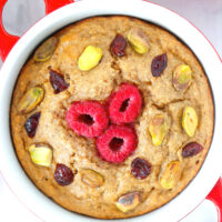 Closeup top view of Cranberry Pistachio Baked Oats in a red ramekin surrounded by Christmas baubles.