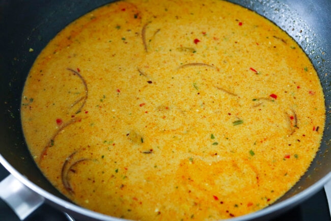 Khao soi curry broth in a wok.