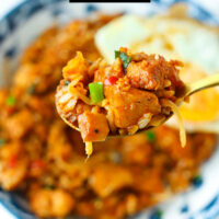 Spoon holding up a bite of kimchi chicken fried rice. Text overlay "Kimchi Fried Rice with Chicken" and "thatspicychick.com".