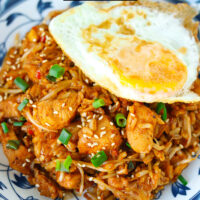 Closeup front view of plate with kimchi chicken fried rice and a fried egg. Text overlay "Kimchi Fried Rice with Chicken" and "thatspicychick.com".