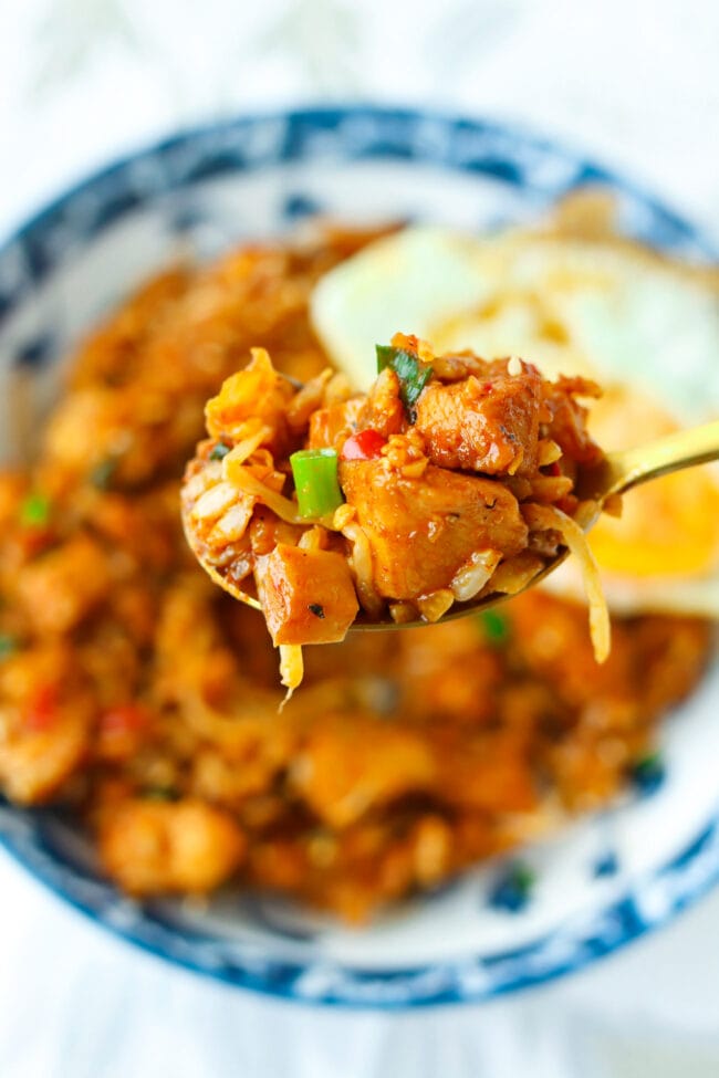 Spoon holding up a bite of kimchi chicken fried rice.