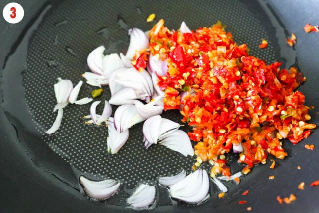 Sliced shallot and smashed garlic chilies paste sizzling in oil in a wok,