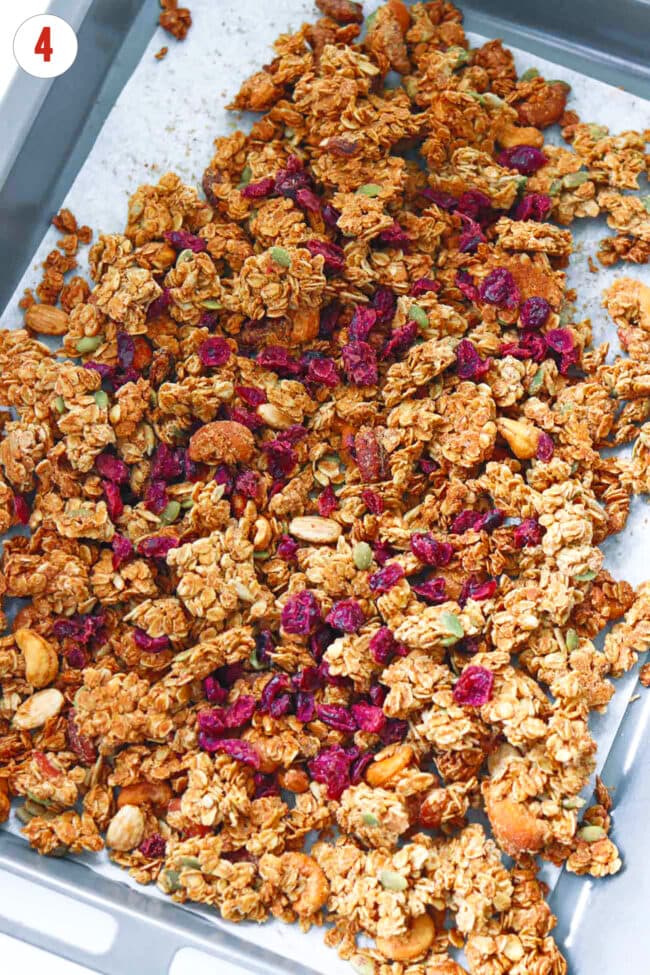 Stirred through dried cranberries in baked granola on baking tray.