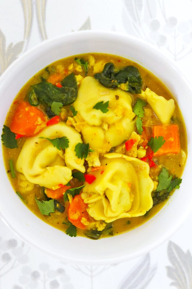 Thai yellow curry tortellini soup in a white bowl.