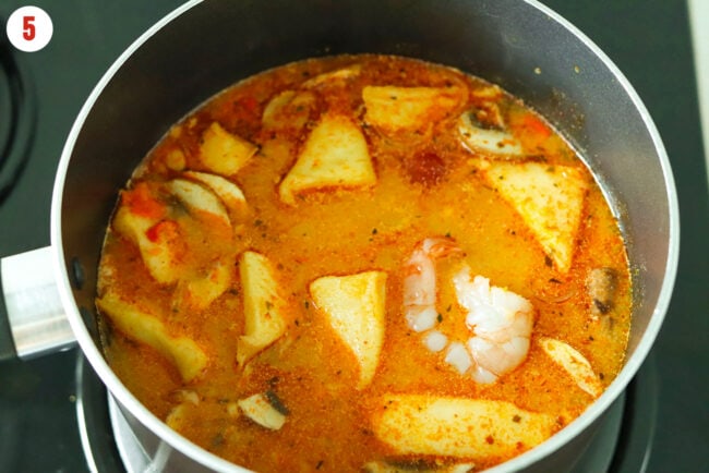 Added shrimp and fish blocks to spicy Thai soup in pot.