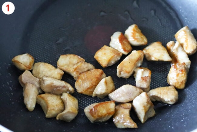 Cooking chicken pieces in a wok.