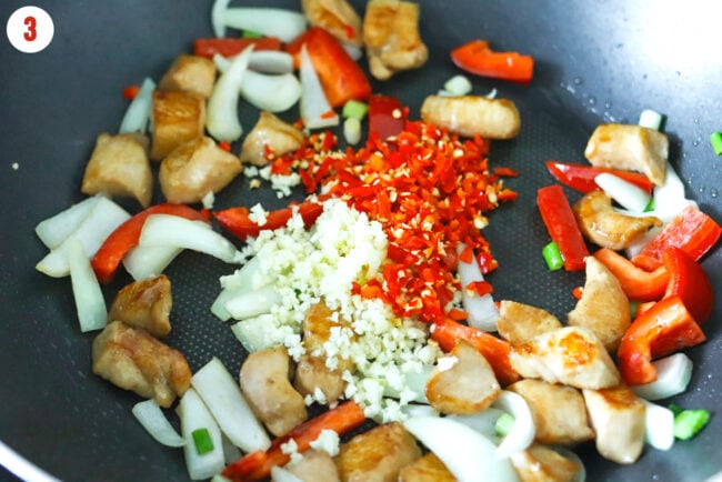 Added chopped garlic and red chilies to wok with chicken, onion and red bell pepper.