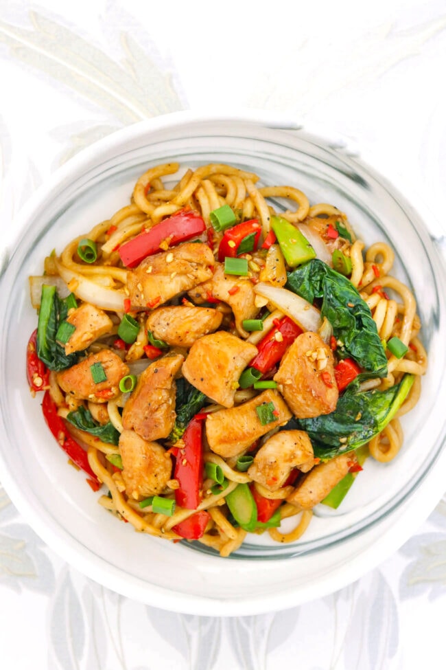 Stir-fried black pepper noodles with chicken on a plate.