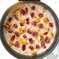 Bowl with carrot overnight oats topped with dried cranberries and walnuts. Text overlay "Carrot Cake Protein Overnight Oats" and "thatspicychick.com".