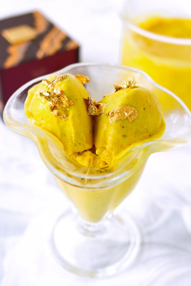 Closeup of Ninja Creami Golden Milk Ice Cream topped with gold flakes in ice cream dish.