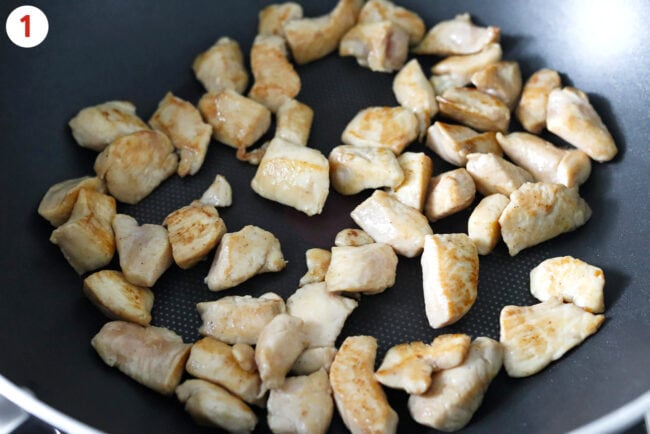 Cooking marinated chicken pieces in a wok.