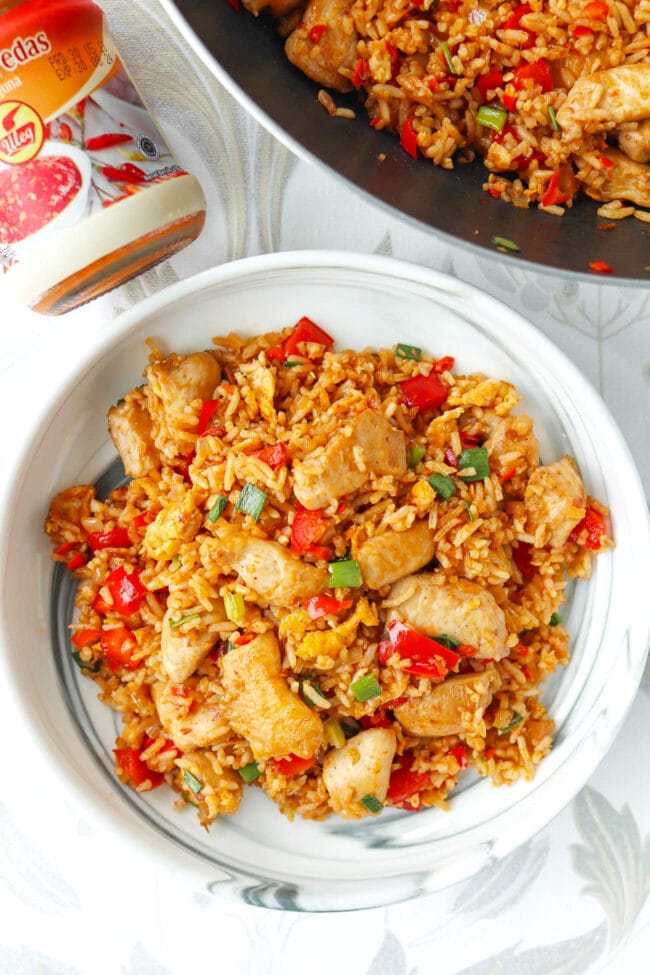Sambal chicken fried rice on a plate and in a wok and sambal jar.