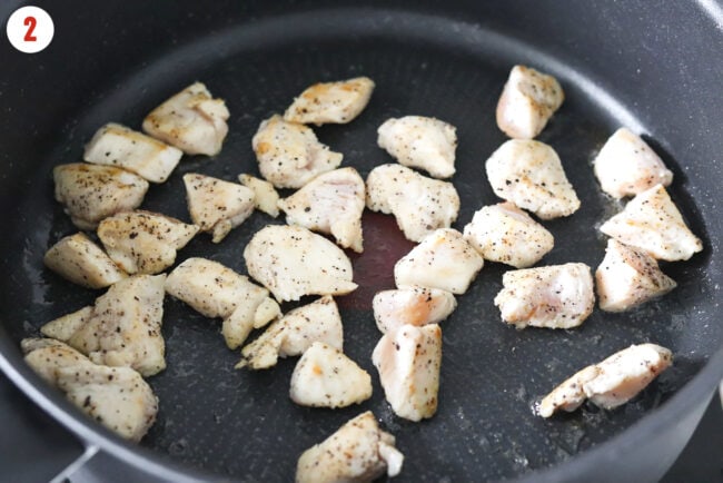 Cooking seasoned chicken pieces in a pan with bacon grease.
