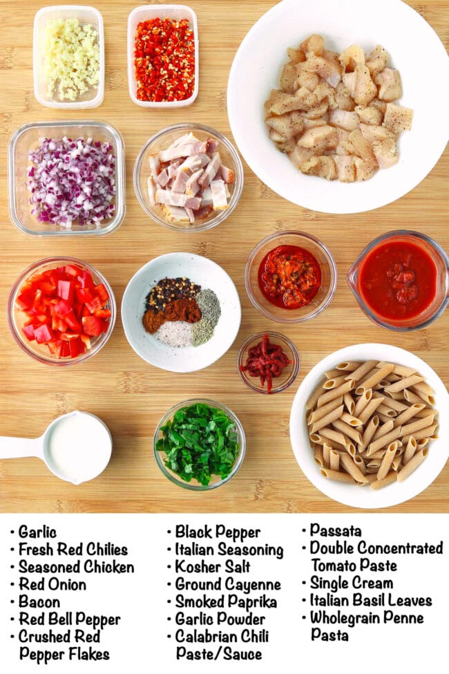 Labeled ingredients for Spicy Chicken and Bacon Tomato Pasta on a wooden board.