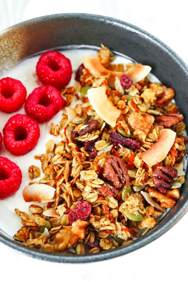 Close-up front view of bowl with yogurt, carrot cake granola and raspberries.