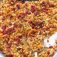 Baking sheet with granola on a large serving spoon. Text overlay "Carrot Cake Granola", "Healthy | Gluten-Free | Vegan" and "thatspicychick.com"