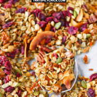 Close-up of spoon with granola on a baking sheet with carrot granola. Text overlay "Carrot Cake Granola", "Healthy | Gluten-Free | Vegan" and "thatspicychick.com"