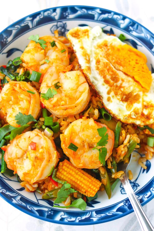 Tom yum fried rice with shrimp on a plate closeup with a spoon.