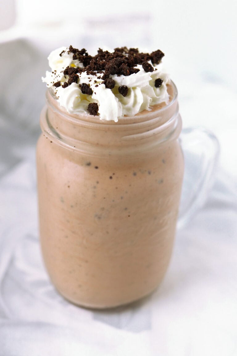 Cookies and Cream Protein Shake in a mason glass topped with whipped cream and crushed Oreos.