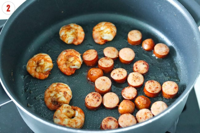 Cooked sliced Andouille sausage and Cajun shrimp in a skillet.