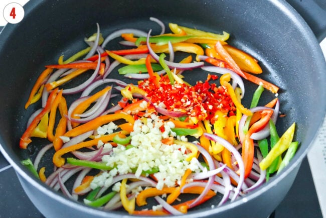 Minced garlic and red chilies added to pan with sauteed slcied red onion and bell peppers.