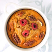 Healthy gingerbread baked oats in a ramekin with raspberries and pecans.