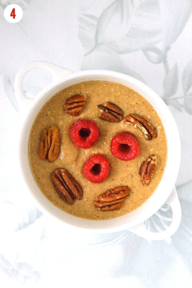 Gingerbread baked oatmeal batter in a ramekin topped with pecans and raspberries.