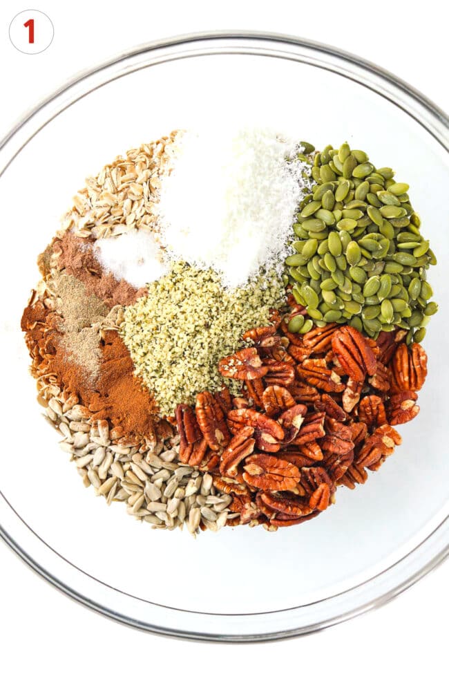 Pecans, sunflower seeds, pumpkin seeds, hemp hearts, warm spices, salt, oats, and desiccated coconut in a large mixing bowl.
