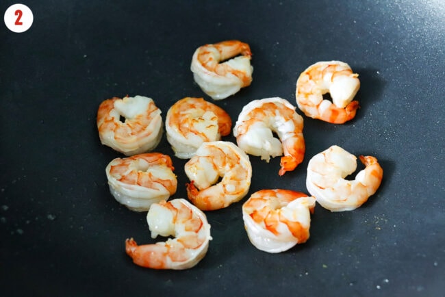 Seared shrimp in a large wok.