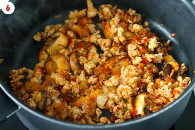 Cooked ground chicken with kimchi, mushrooms and aromatics in a skillet.