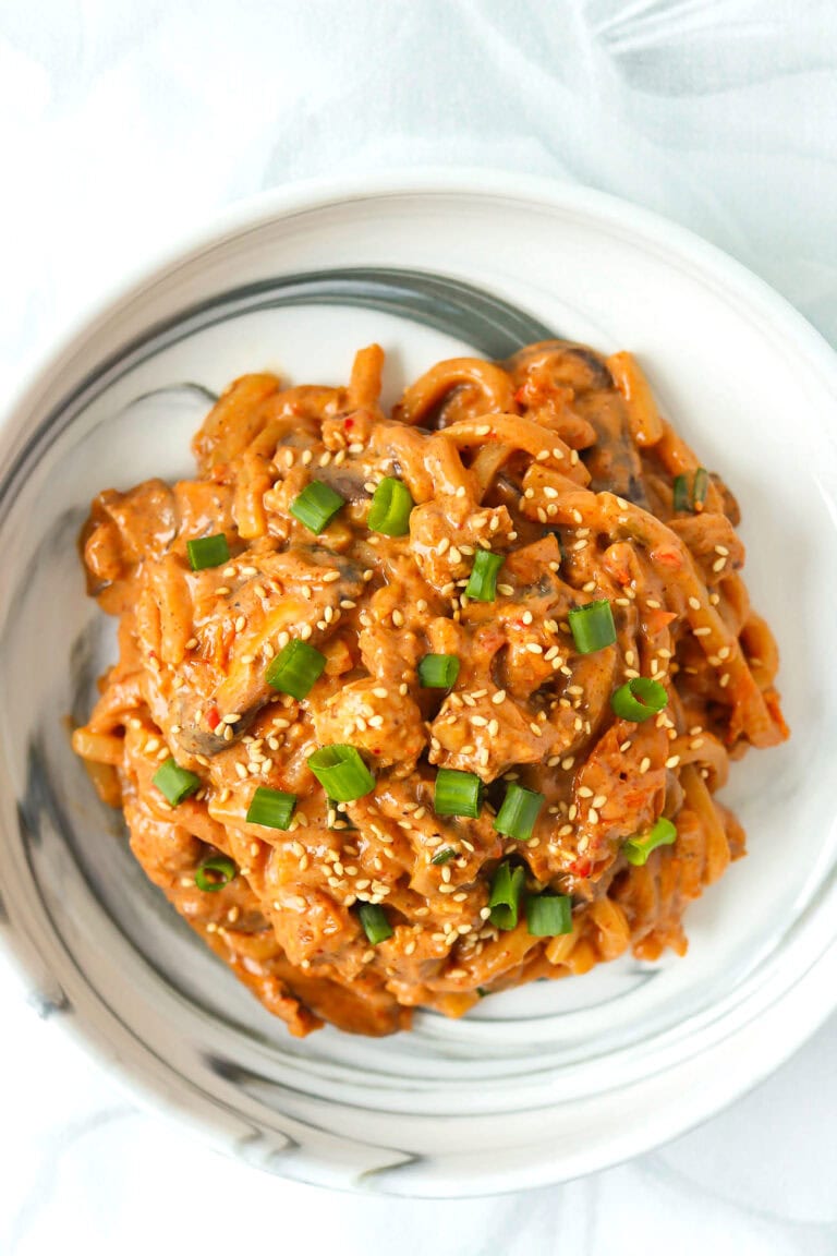 Top view of plate with creamy kimchi udon noodles with blended tofu sauce.