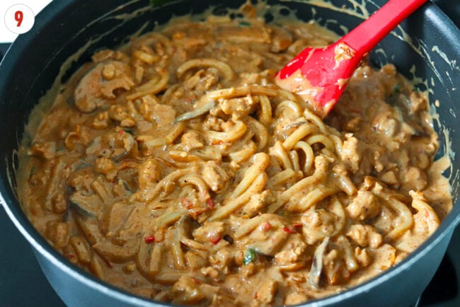 Creamy kimchi udon noodles with blended tofu sauce in a skillet with a silicone spatula.