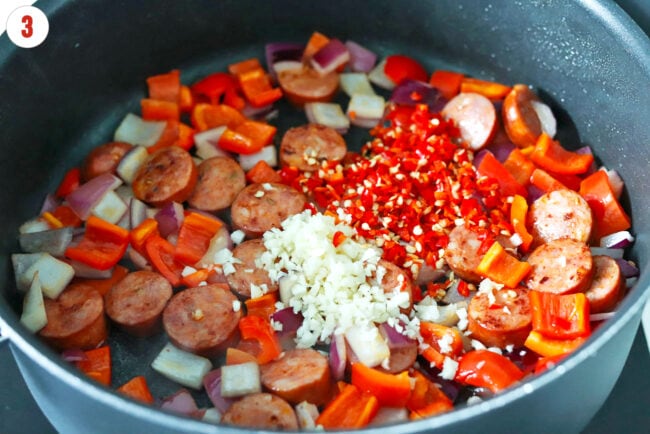 Garlic and chilies added to pan with browned sausage, red onion, and red bell pepper.