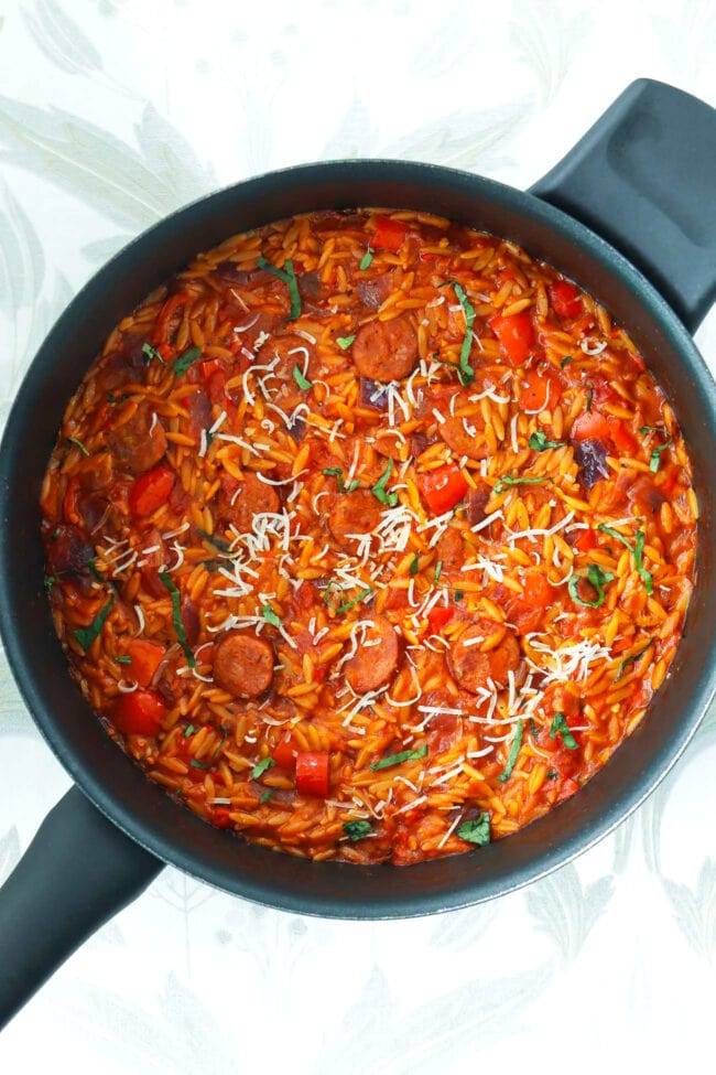 Top view of spicy Cajun orzo with sausage and peppers in a pan.