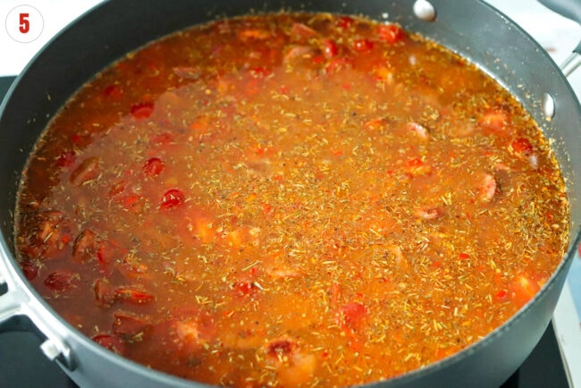 Water, broth, base and seasonings in pan with tomatoes, orzo and sausage mixture.