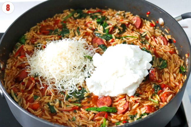 Ricotta and grated parmesan in pan with spicy Italian sausage with orzo.