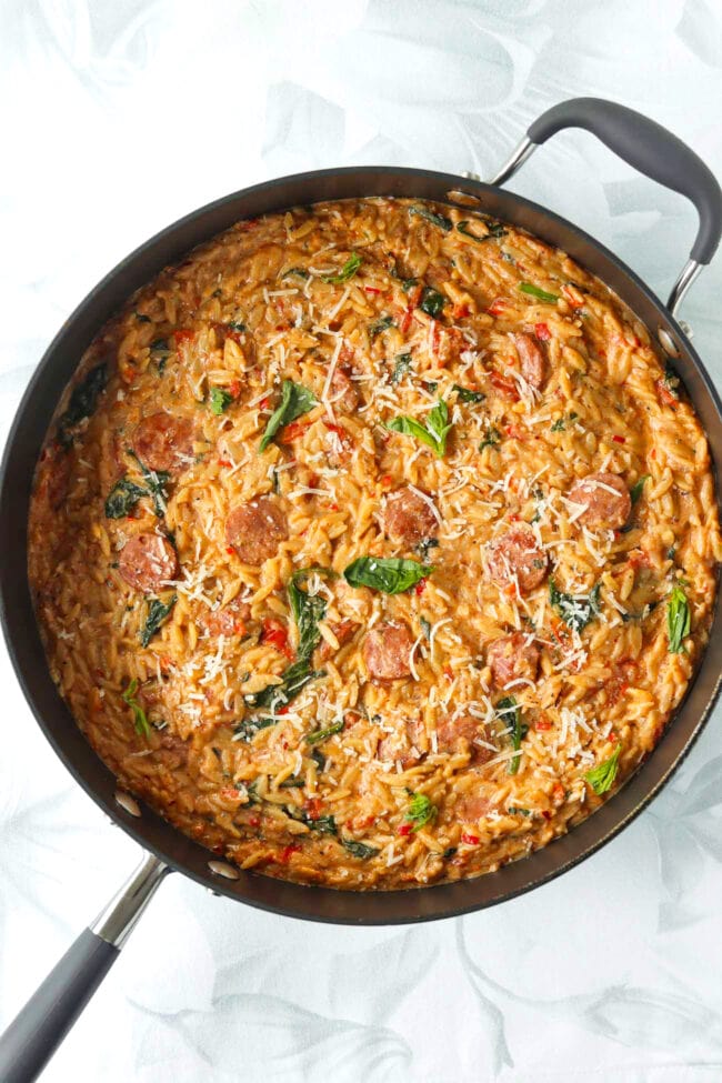 Top view of pan with spicy Italian sausage with orzo.