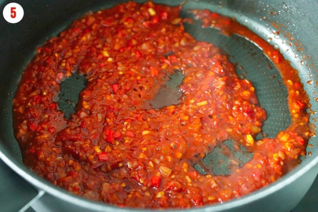 Close-up of simmering spicy Calabrian pepper, tomato, shallots and garlic mixture in a nonstick pan.