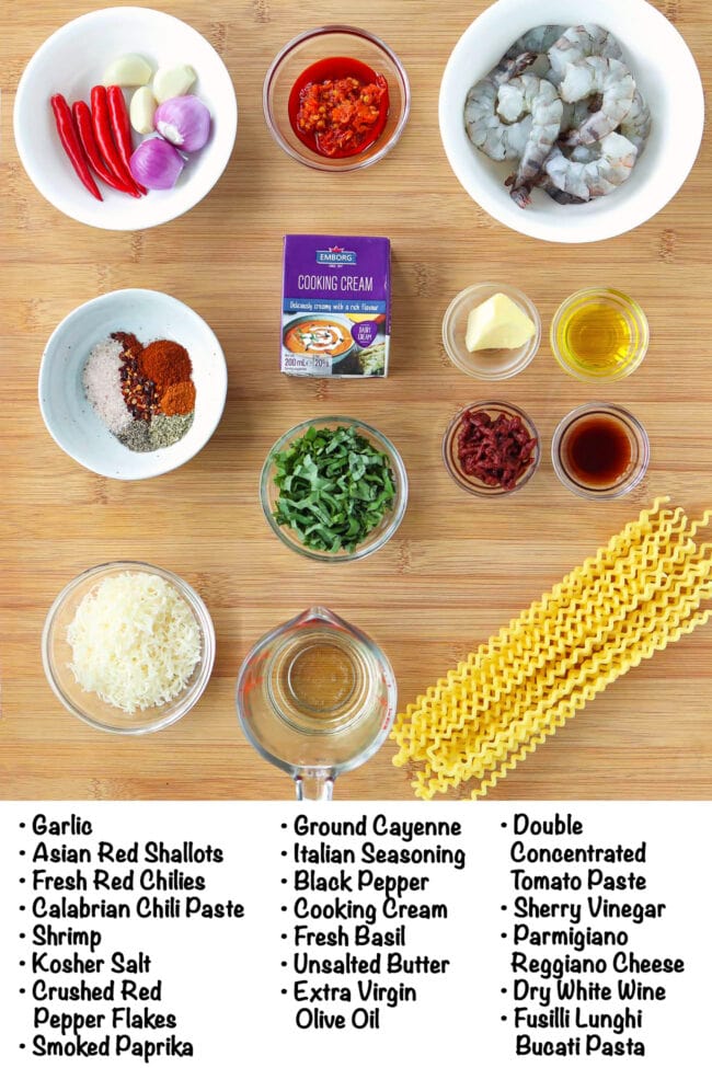 Labeled ingredients for creamy Calabrian chili pasta with shrimp on a wood board.