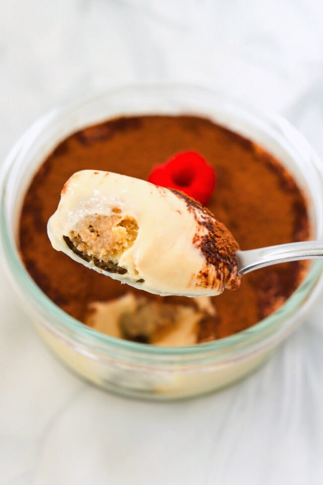 Spoon holding up a bite of cottage cheese tiramisu.