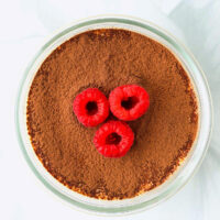 Single serve cottage cheese tiramisu topped with cocoa powder and raspberries.