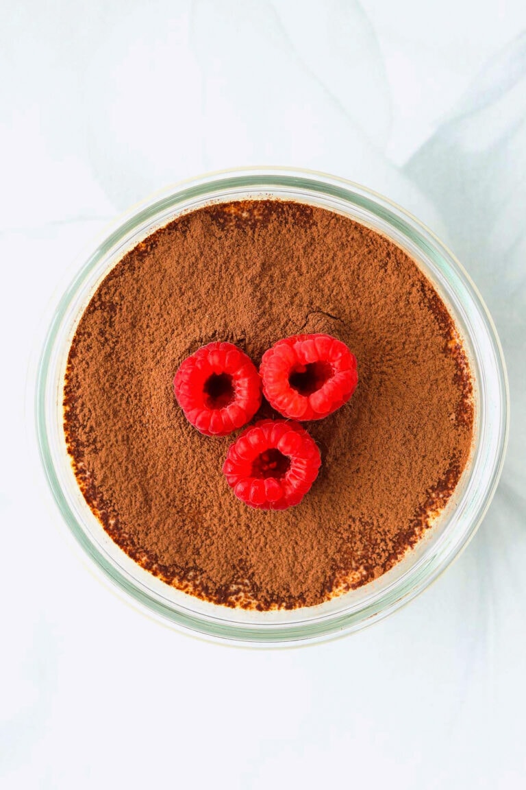 Single serve cottage cheese tiramisu topped with cocoa powder and raspberries.