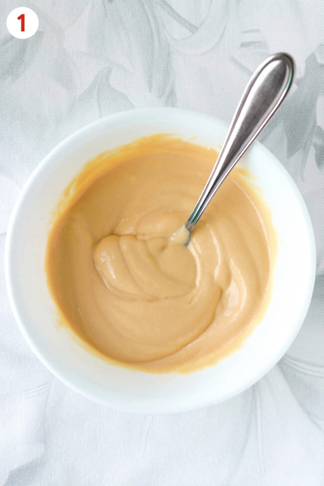 Blended cottage cheese, dulce de leche, and maple syrup mixture in a bowl with a spoon.