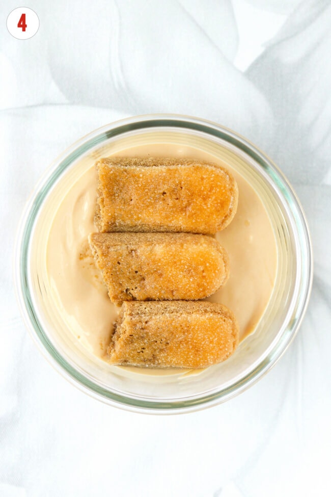 Espresso-soaked ladyfingers on dulce de leche cottage cheese layer in a small dish.