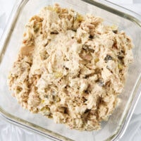 Cottage cheese tuna salad with dill pickles in a square glass meal prep dish.