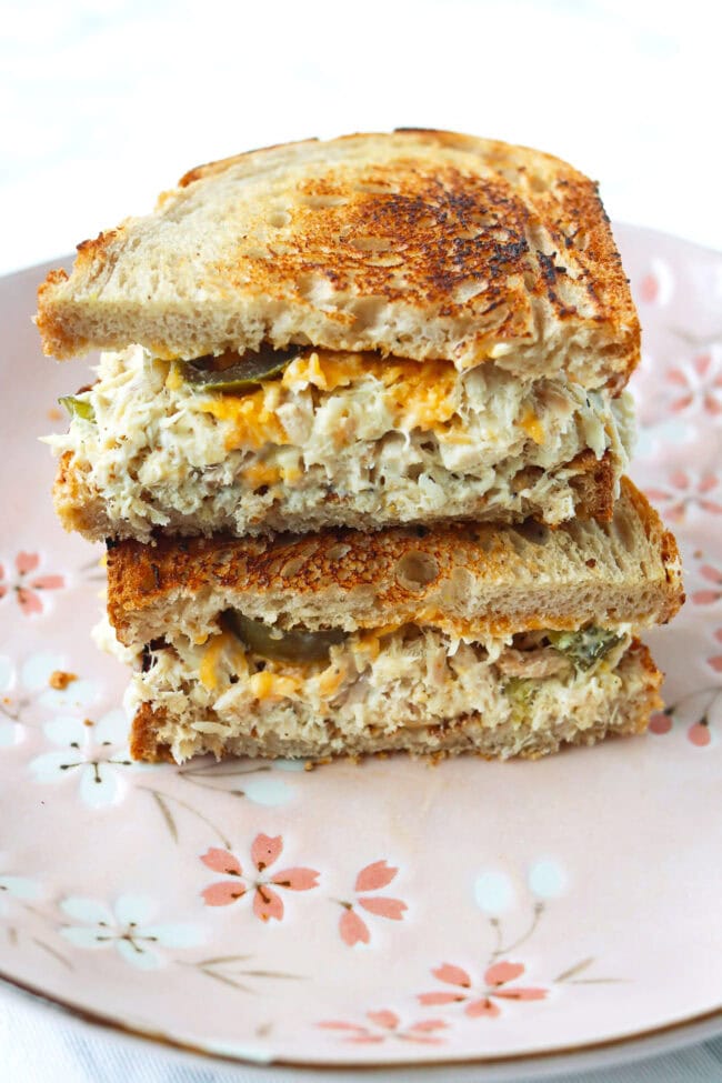 Healthy tuna salad toasted sourdough bread sandwich with cheddar cheese and pickled jalapeños stacked on a plate.