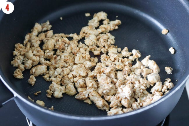 Cooked Cajun seasoned lean ground chicken breast in a black pan.